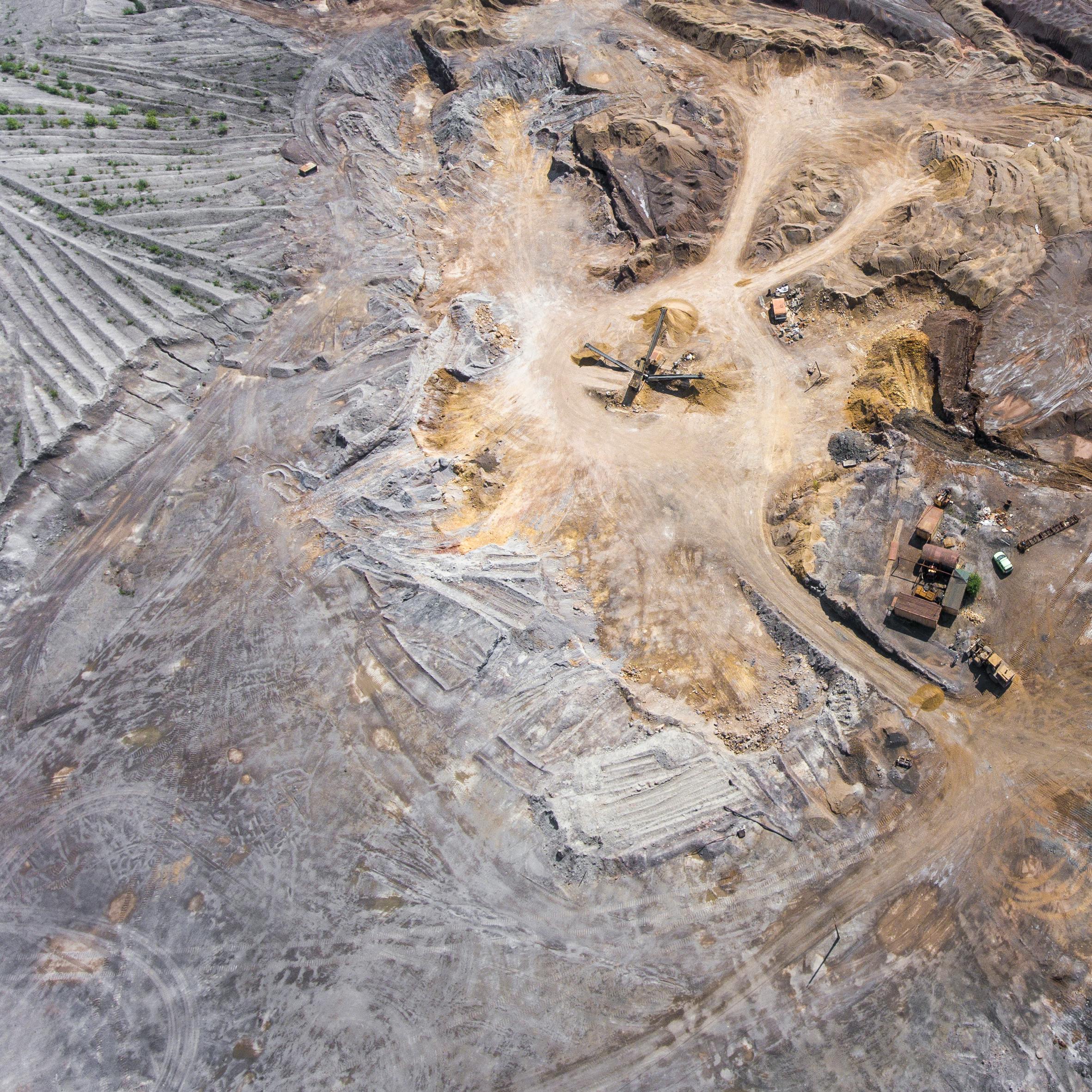 An expansive aerial view of a mining site displaying machinery and earth patterns.